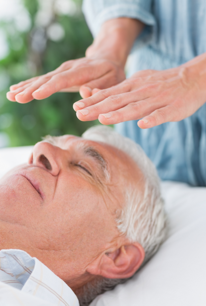 An older guy receiving a reiki session to balance his energy.