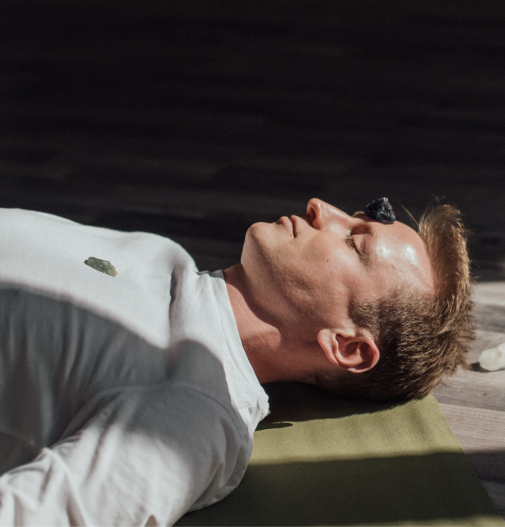 A guy laying on a yoga mat doing breathwork.