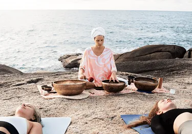 group gathered around sound bowls meditating by the sea