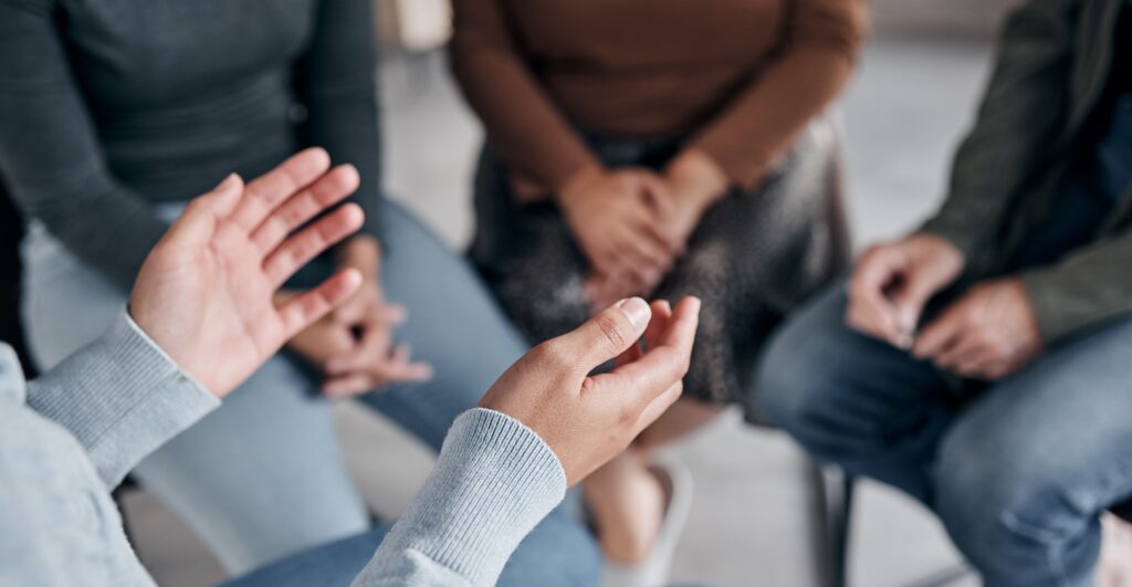 clients sitting in a circle speaking in group therapy