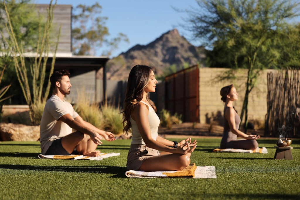 3 people meditating outside
