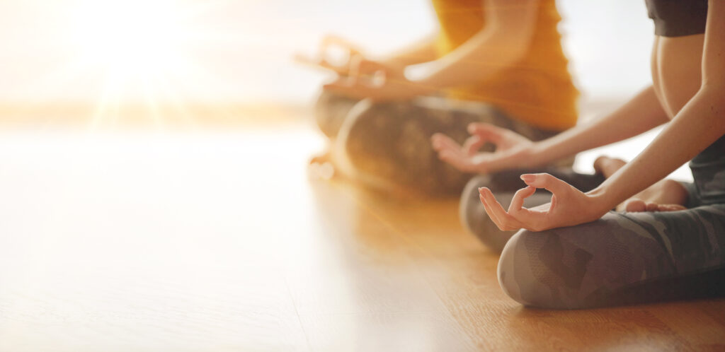 women meditating together as the sunlight comes in