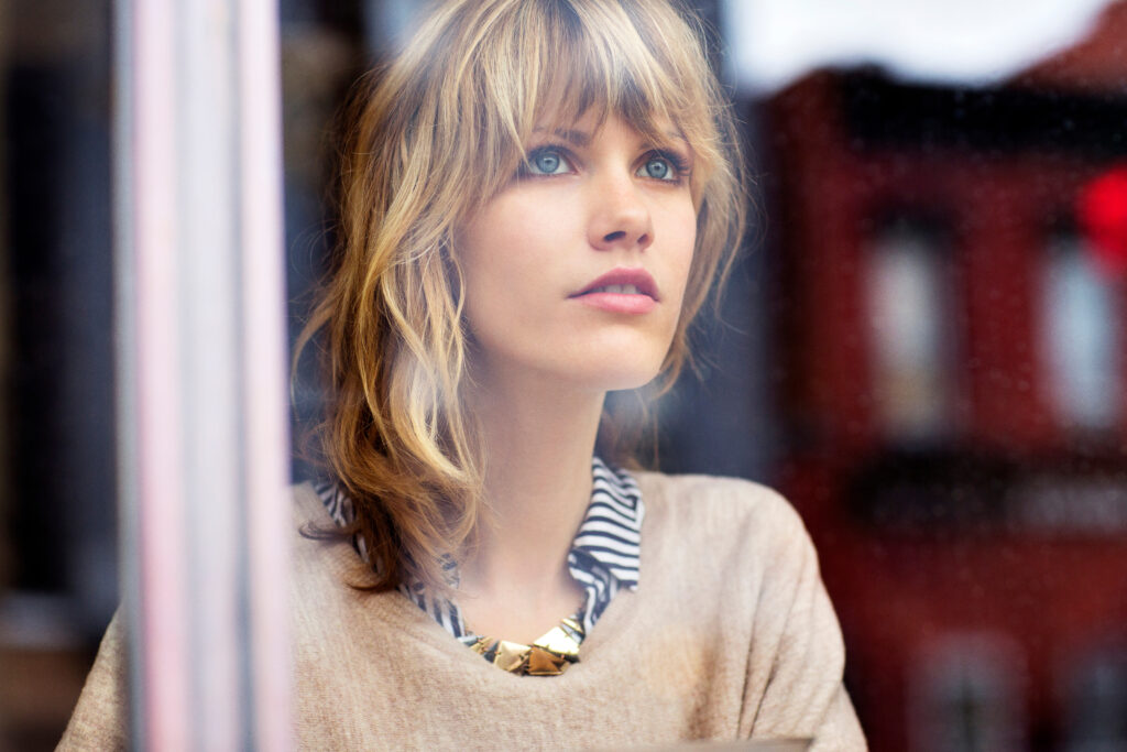 Young woman looking through window in cafe reflecting