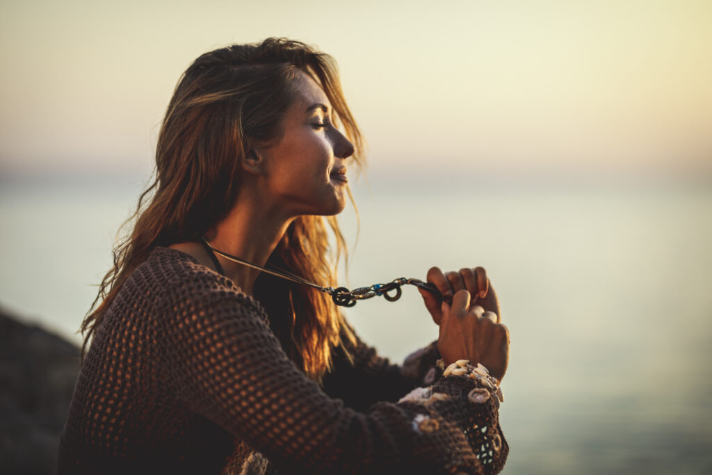 young woman is relaxing near water at the sunset.