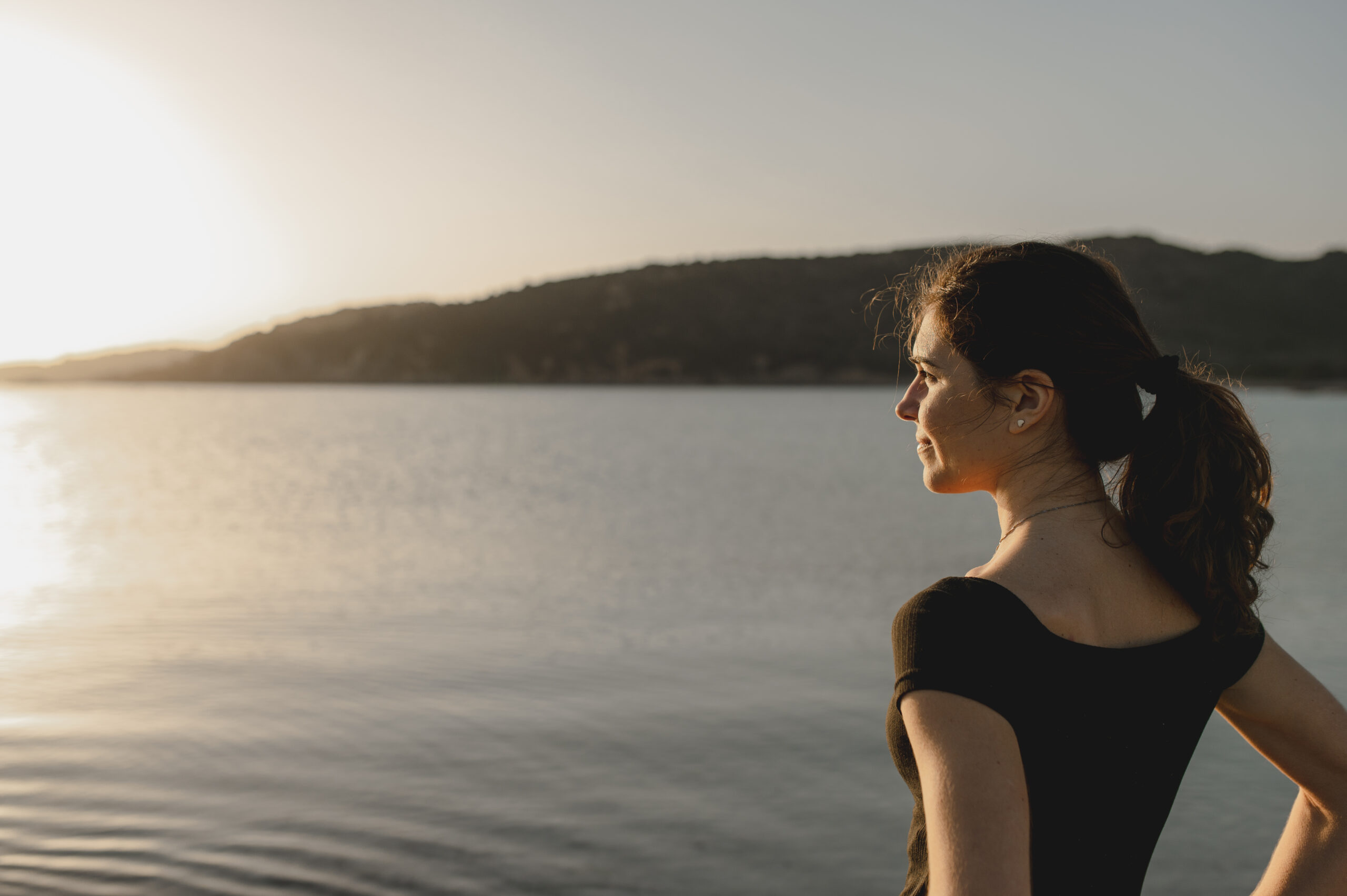 A woman taking a slow breath outdoors by the water