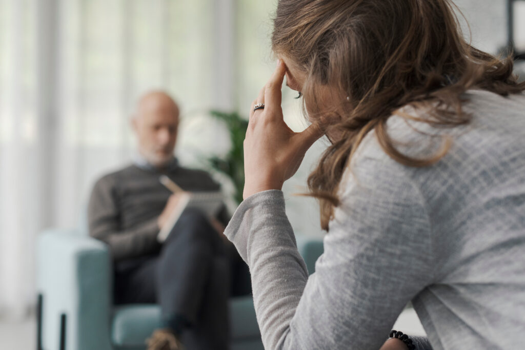 Professional therapist writing notes while listening to his patient during a psychotherapy session