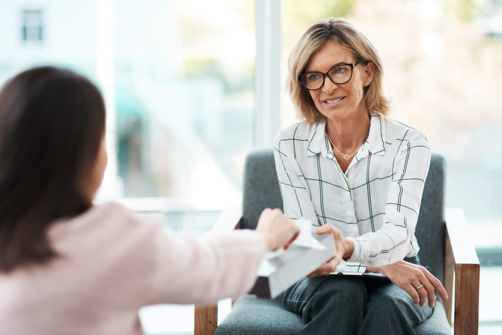 Shot of a mature psychologist offering her patient tissues during a therapeutic session