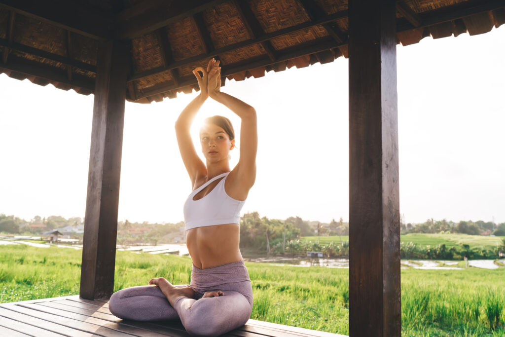 Caucasian woman in sportswear meditate in lotus pose and looking away thinking about hatha yoga practice, attractive healthy girl enjoying free time for tranquil enlightenment during sunshine