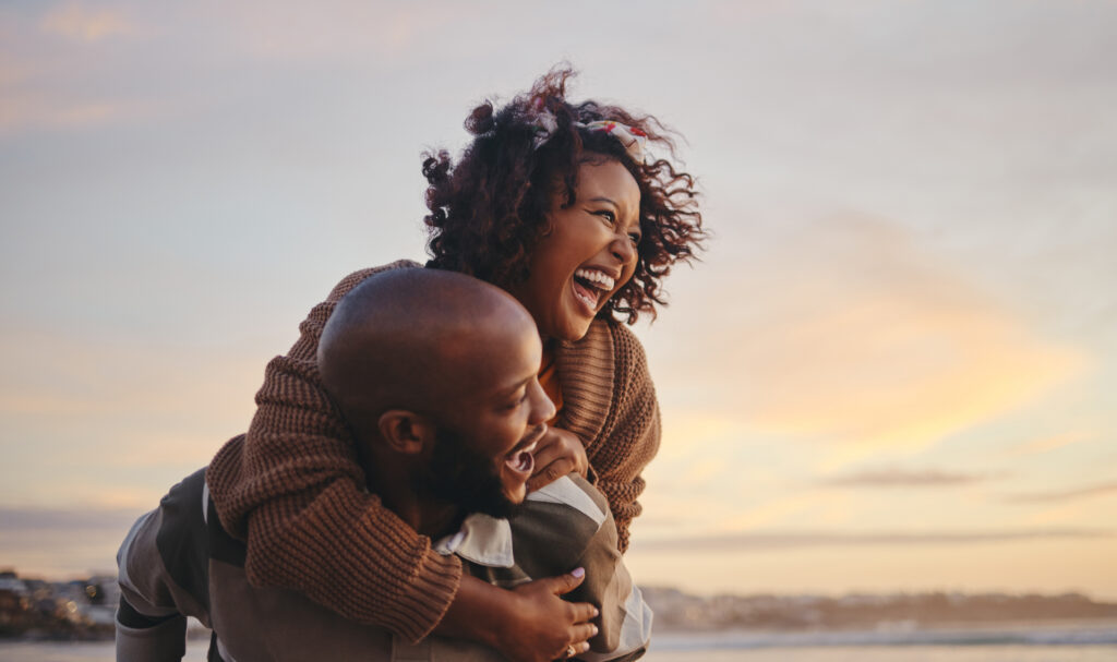 a woman and her husband laugh by the beach