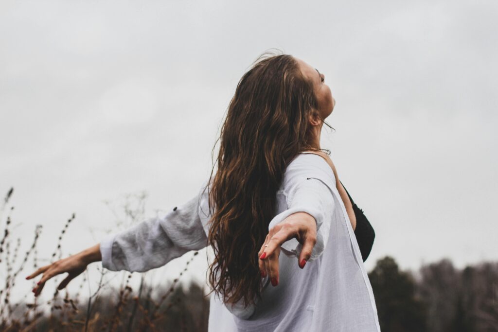 back of young woman with her arms out