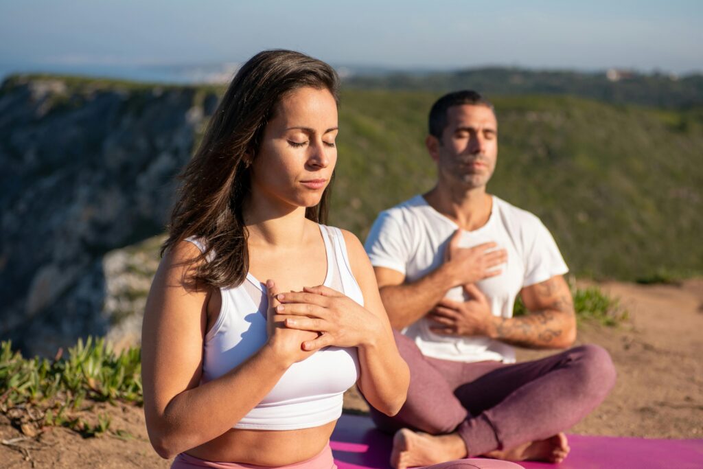 woman and man meditating with mountain backdrop