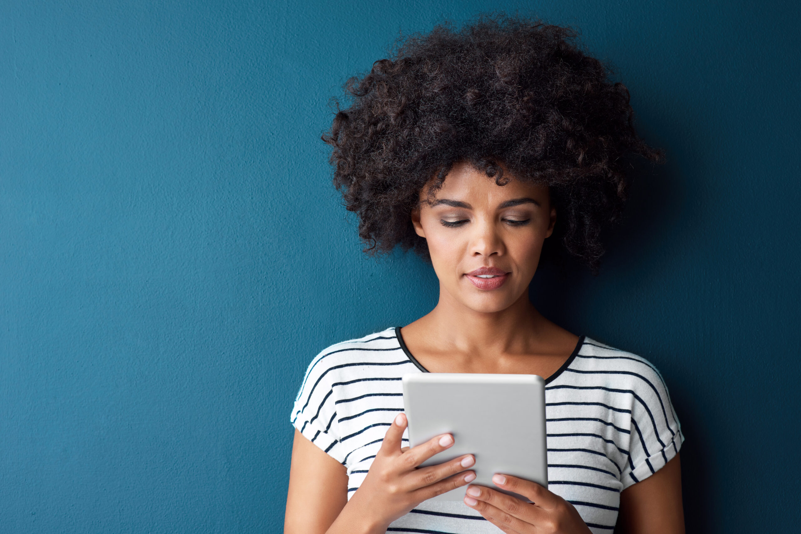 A woman smiling as she reads on a tablet