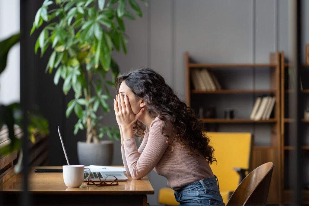 A woman at her desk with her hand to her face, overwhelmed